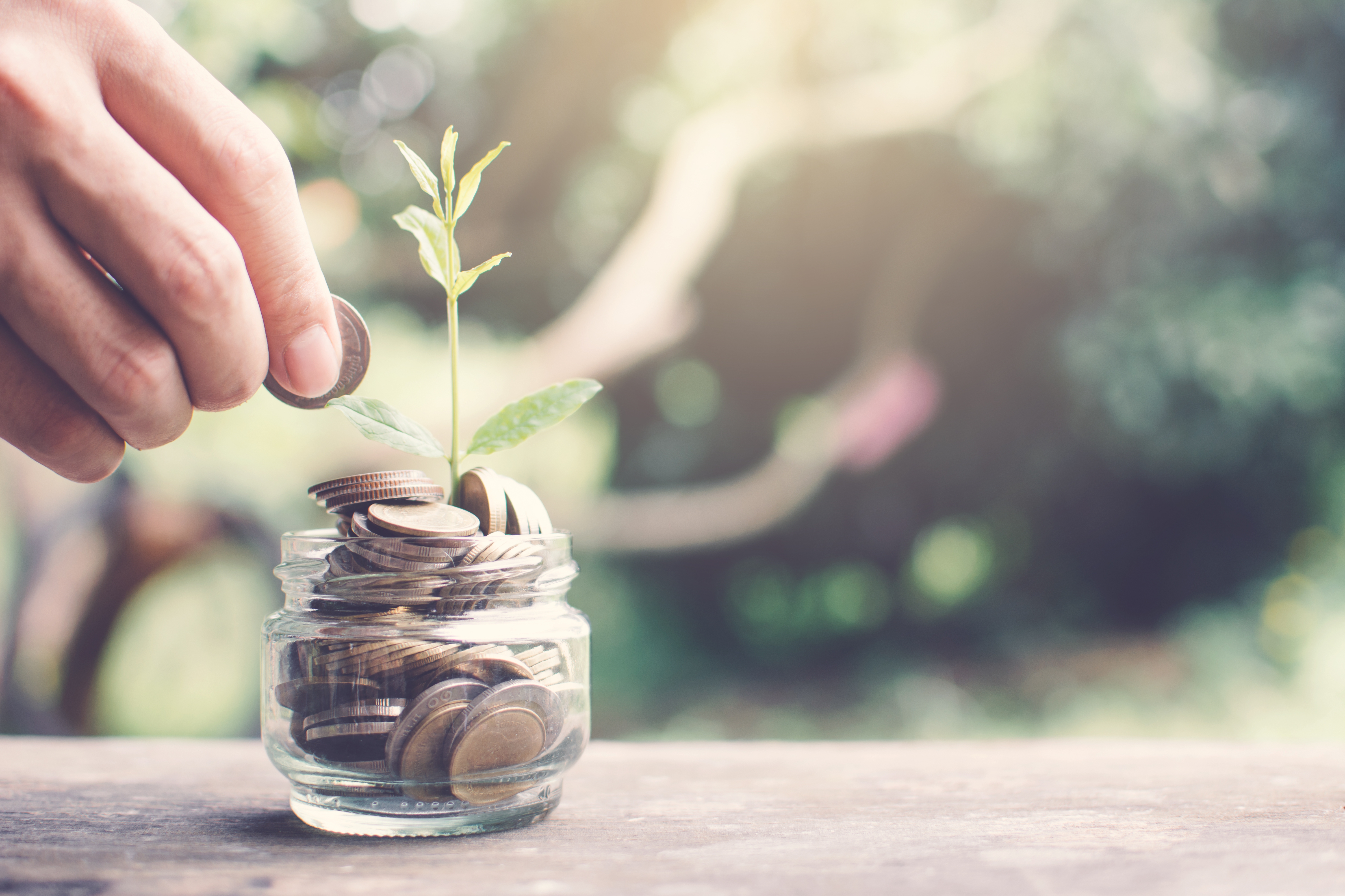 hand-of-woman-saving-coins-in-glass-jar-on-table-in-nature-bokeh-background-color-vintage-style_t20_a7JVOP