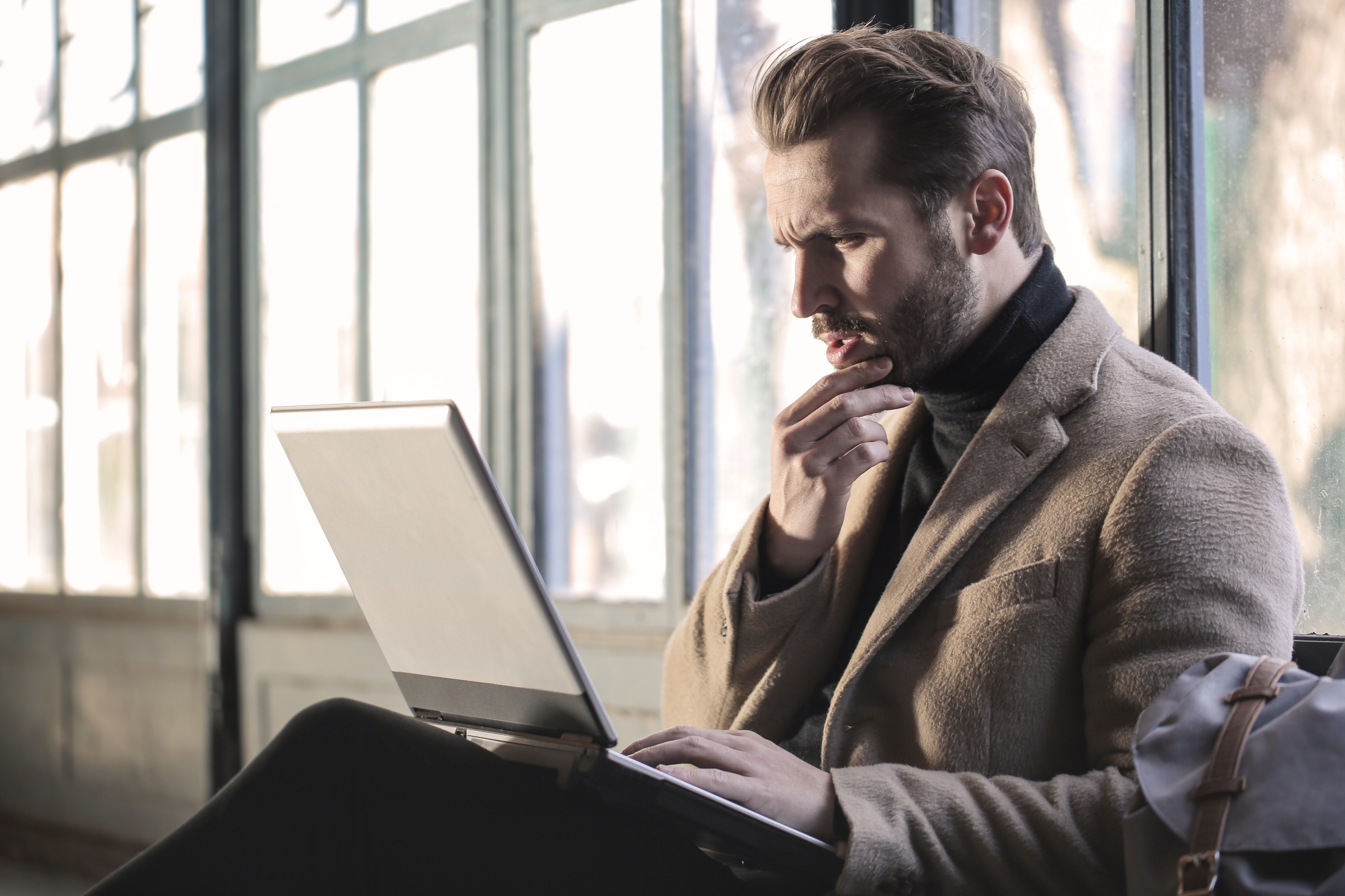 man-wearing-brown-jacket-and-using-grey-laptop-874242